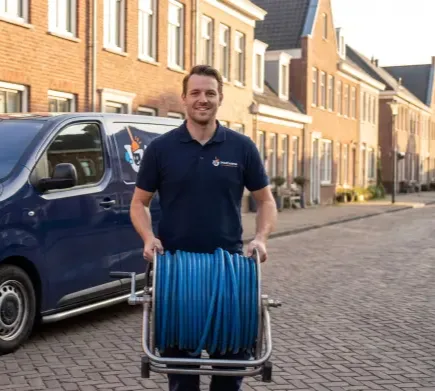 Van Dijk monteur met hogedrukhaspel naast de servicebus in een woonstraat